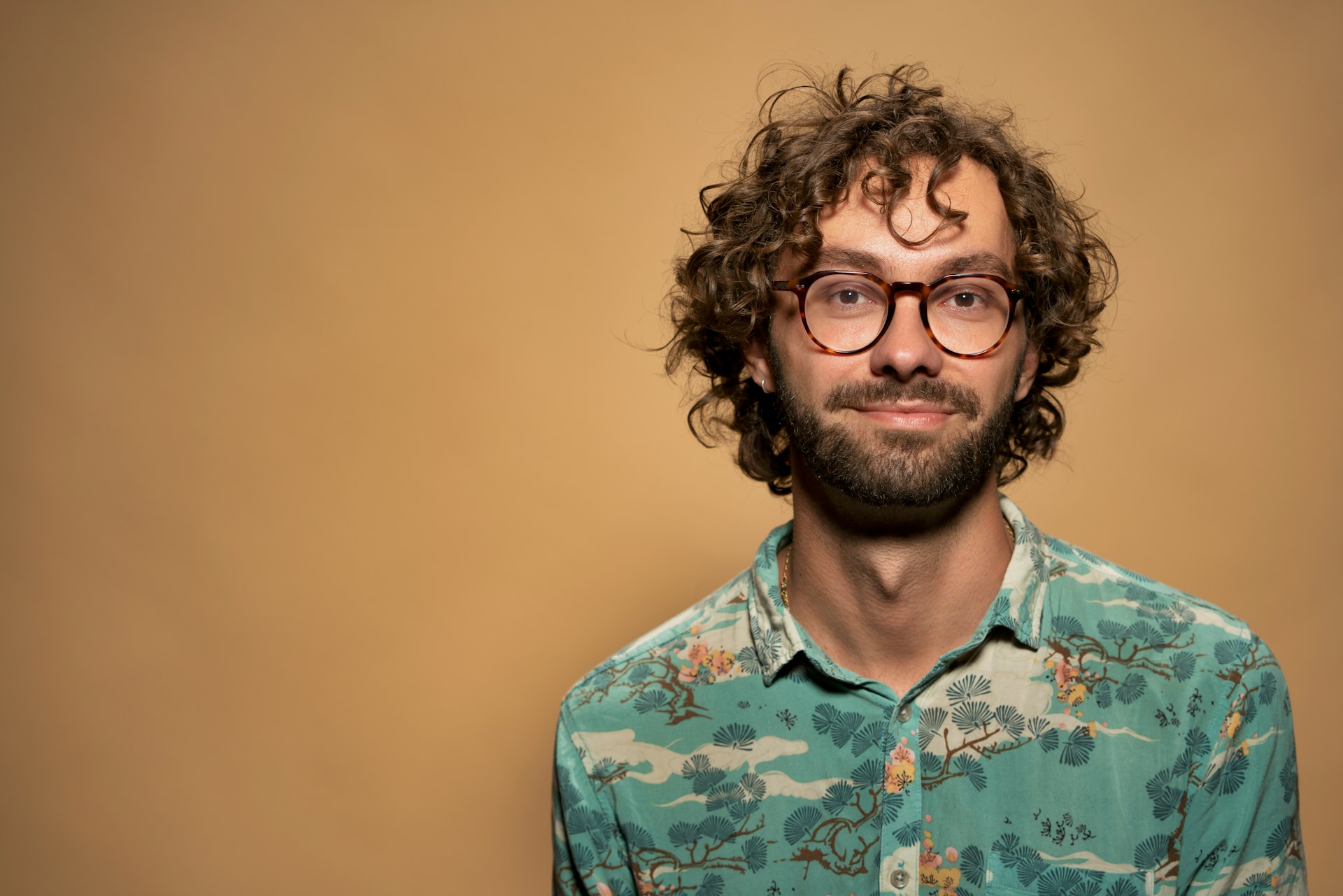 a man with curly hair and glasses looking at the camera